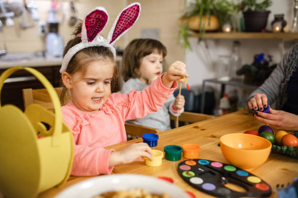 istock Creative cute female toddlers painitnig Easter eggs 1211124710