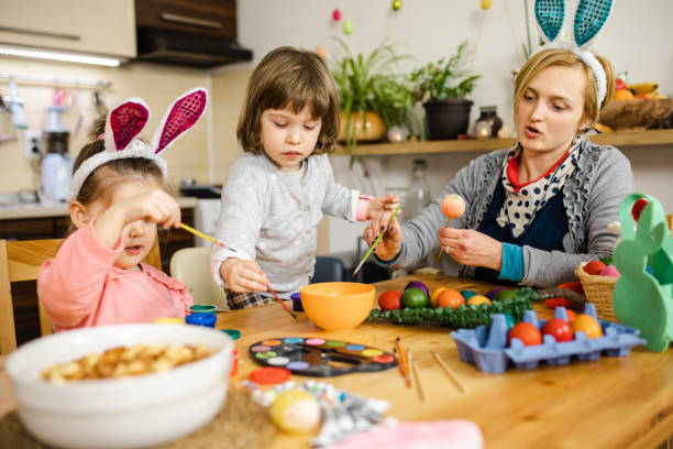 istock Mother assisting daughter in painting Easter egg at home 1211125245