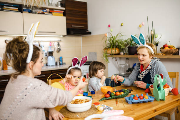 istock Curious sisters coloring Easter egg with watercolor paint while their mothers helping them 1211126824