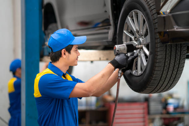 asiatische mechaniker wechsel autorad in auto-reparatur-shop mit luftgewehr-werkzeug. - mechanician stock-fotos und bilder