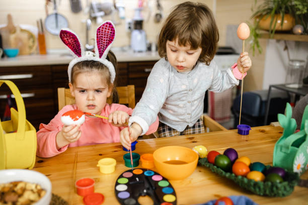 istock Dedicated little girls painting their easter eggs in different colors 1211127352