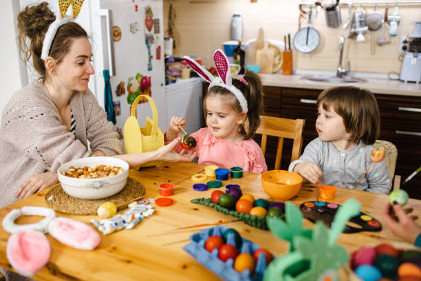 istock Little girls coloring Easter egg with mom 1211127973