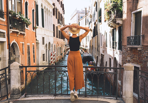Young woman travel Italy. Vacation in Europe. Girl enjoy beautiful view in Venice. Female tourist walking on streets in Venezia. Fashion blogger take photo on scenic bridge of Grand Canal.