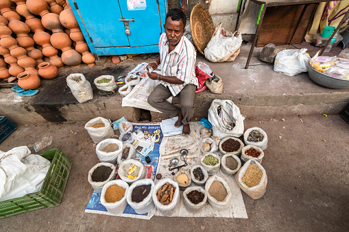 Warangal, Telangana, India - March 2019: A wide angle portrait of a street vendor selling spices by the roadside in the city of Warangal.