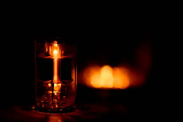A single glowing vacuum tube in the dark. Other tube blowing in the background but outside the shallow depth of field.