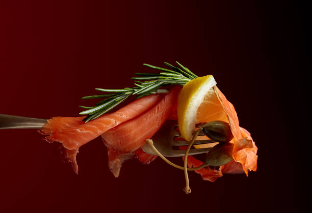 Trout fillets, lemon slice, capers and rosemary on a dark background. Copy space.