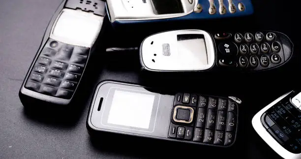Heap of vintage mobilephones on a black background.