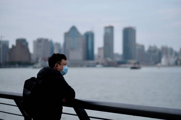 un homme utilisant le masque chirurgical s’appuyant sur la balustrade au bund en chine - hubei province photos et images de collection