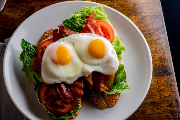 istock Bacon Lettuce Tomato Sandwich Classic American Diner Breakfast/ Brunch Restaurant menu favorite, BLT. Sunny side up eggs served open face. Crispy Bacon, fresh tomato slices, crisp lettuce with eggs. 1211157759