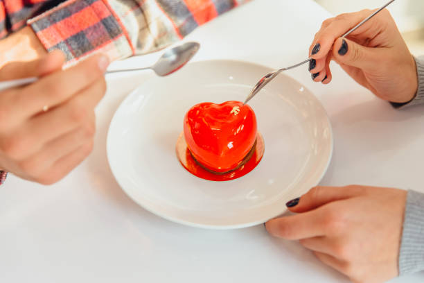 istock Mousse dessert in heart-shape and people hands, holding spoons, tasting this candy, celebrating Valentine's Day. 1211157771