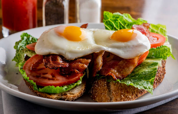 istock Bacon Lettuce Tomato Sandwich Classic American Diner Breakfast/ Brunch Restaurant menu favorite, BLT. Sunny side up eggs served open face. Crispy Bacon, fresh tomato slices, crisp lettuce with eggs. 1211157816