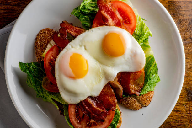 istock Bacon Lettuce Tomato Sandwich Classic American Diner Breakfast/ Brunch Restaurant menu favorite, BLT. Sunny side up eggs served open face. Crispy Bacon, fresh tomato slices, crisp lettuce with eggs. 1211157897