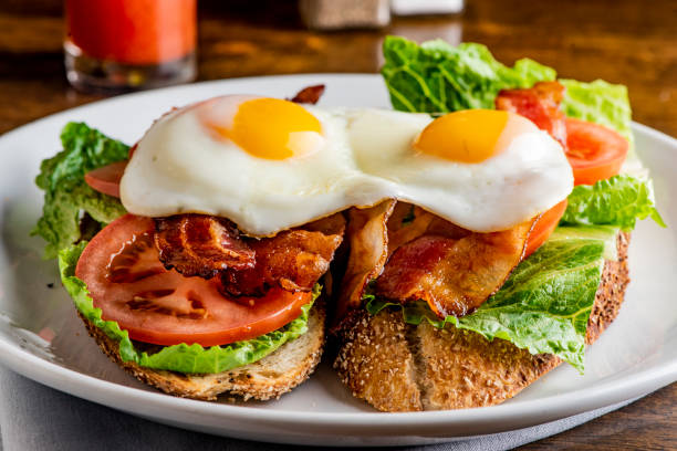 istock Bacon Lettuce Tomato Sandwich Classic American Diner Breakfast/ Brunch Restaurant menu favorite, BLT. Sunny side up eggs served open face. Crispy Bacon, fresh tomato slices, crisp lettuce with eggs. 1211157901