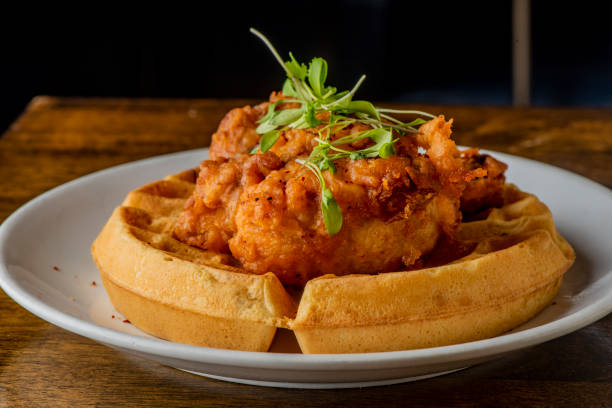 pollo & gofres. classic american diner style breakfast o brunch menú elemento favorito. pollo frito casero crujiente encima de los gofres caseros de suero de mantequilla cubiertos con mantequilla y jarabe de arce. - waffle chicken fried chicken food fotografías e imágenes de stock