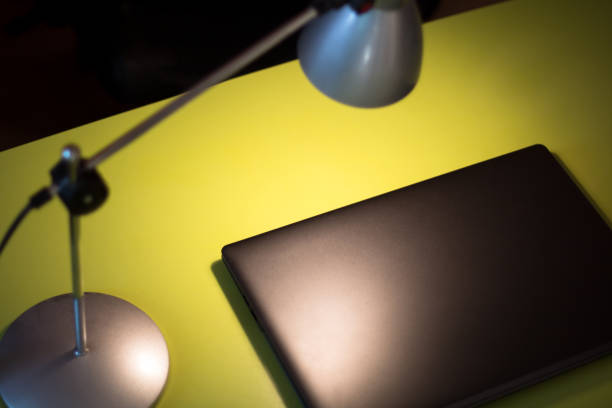 istock closed laptop under lamp light on the green table 1211162976
