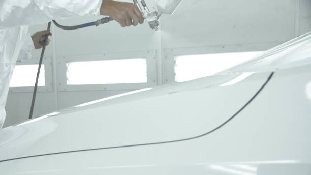 istock Process of painting a white car in a spray booth. Man using a spray gun 1211163420