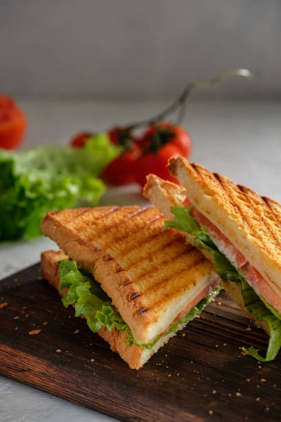 istock Cheese sandwich of toasted bread with a crispy crust with fresh tomatoes and herbs on a wooden board 1211163473