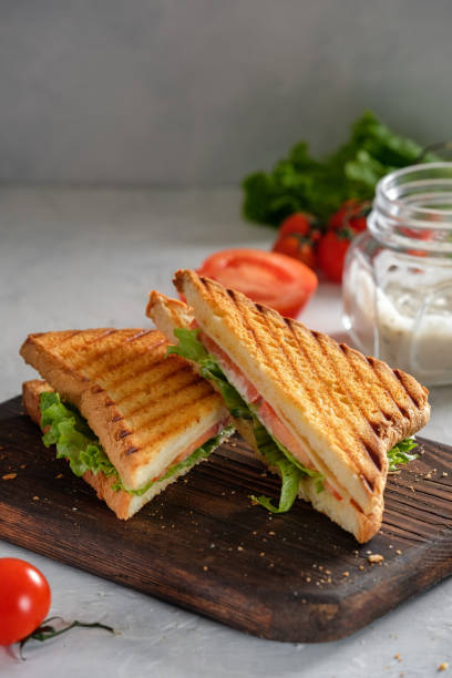 istock Cheese sandwich of toasted bread with a crispy crust with fresh tomatoes and herbs on a wooden board 1211163549