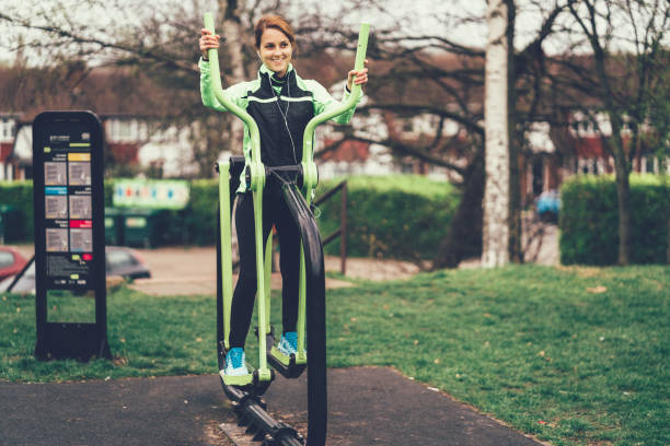 Woman exercising on cross trainer in park