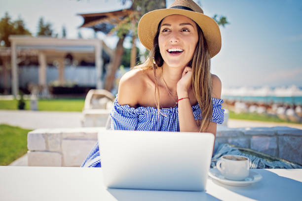 istock Young woman is working and drinking coffee on the beach 1211166403