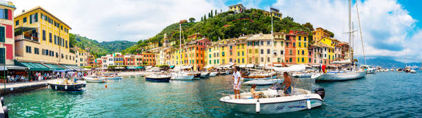Portofino, Italy - July 6, 2019: Panoramic view of the picturesque coastal village of Portofino, Italy. Popular tourist destination and cruise ships in the Ligurian sea.