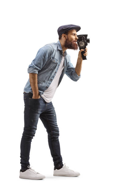 istock Bearded guy recording with 8mm vintage camera 1211170386