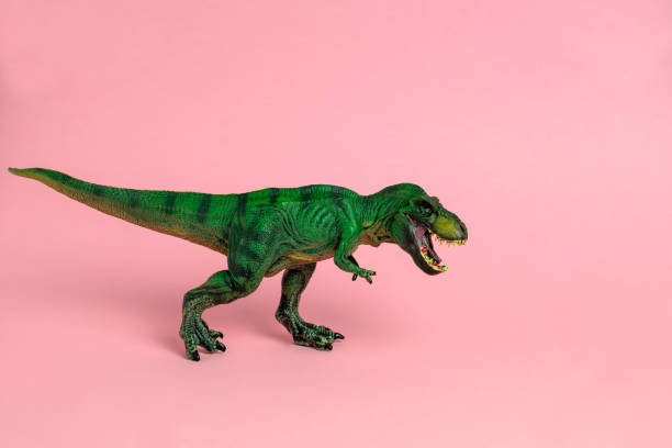istock green dinosaur toy with open mouth on a pastel pink  background 1211170546