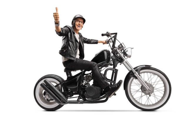 istock Cool mature biker in leather clothes riding a chopper and showing thumb up 1211170824