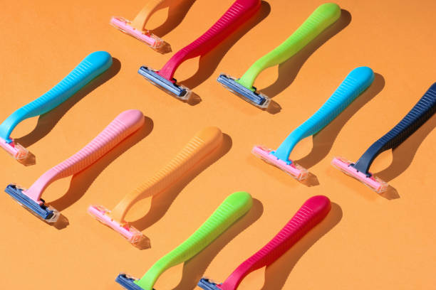 Beauty and fashion pop art concept. Many colored plastic razors on orange background. Minimalism stock photo