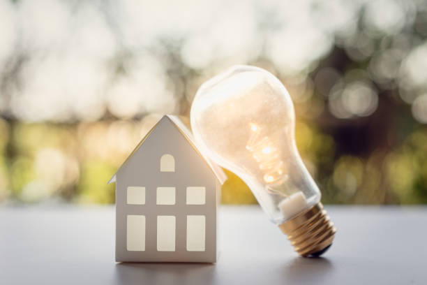 istock Light bulb with white house model on the table, a symbol for construction, Creative light bulb idea, power energy or business idea concept ecology, loan, mortgage, property or home. 1211174629