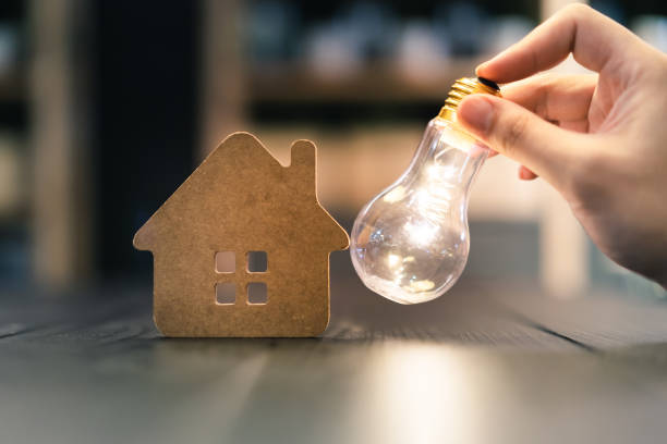 istock Light bulb with wood house on the table, a symbol for construction, Creative light bulb idea, power energy or business idea concept ecology, loan, mortgage, property or home. 1211174684