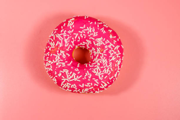 istock Tasty pink donut on pink background 1211177217