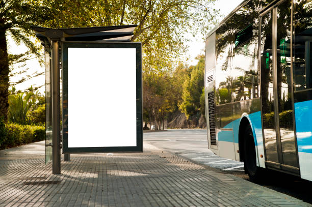 weiße leere vertikale werbetafel an der bushaltestelle an der stadtstraße. im hintergrund von bussen und straßen. skizzieren. poster auf der straße neben der straße - bus station stock-fotos und bilder