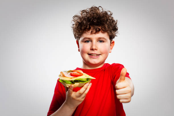 istock Boy eating sandwich showing ok sign 1211186552