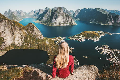 Mujer turista relajarse en la montaña del acantilado admirando increíble paisaje viajando en Noruega estilo de vida saludable concepto aventura al aire libre vacaciones de verano Reinebringen vista aérea islas Lofoten photo