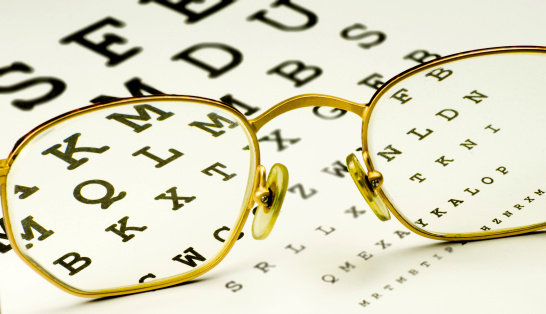 Glass resting on an eyechart. Letters inside the glasses are in focus.
