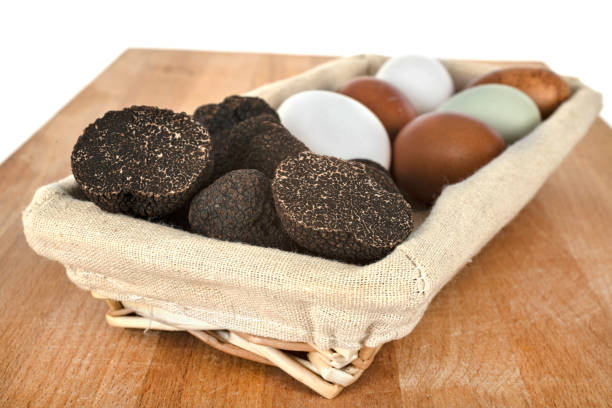 Black truffles and slices on black stone background.