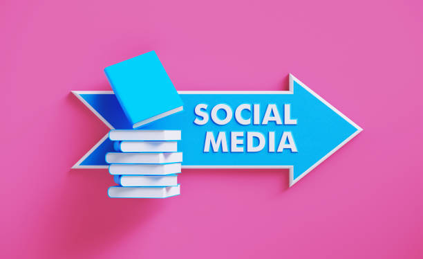 istock Book Stack Sitting over A Blue Arrow Shaped Directional Sign on Pink Background 1211191739