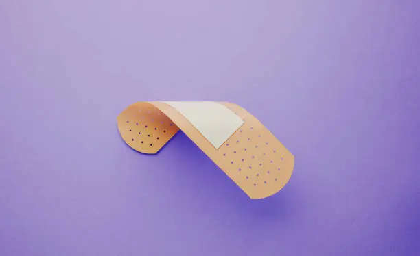 Photo of Adhesive Bandage Plaster Folding on Lavender Background