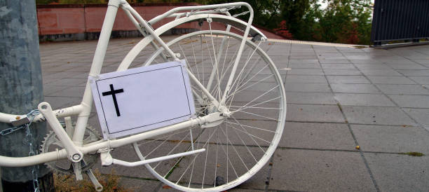 雨の日にドイツの通りで殺されたサイクリストのためのクロスサインとゴーストバイクの記念碑のパノラマビュー。白いゴースト自転車、交通事故で死亡したサイクリストの記念碑 - memorial roadside cross cross shape ストックフォトと画像