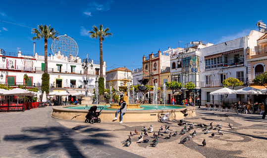View of landmark Cabildo square in Sanlucar de Barrameda, southern Spain, surrounded by restaurants and shops that attract tourists year round.