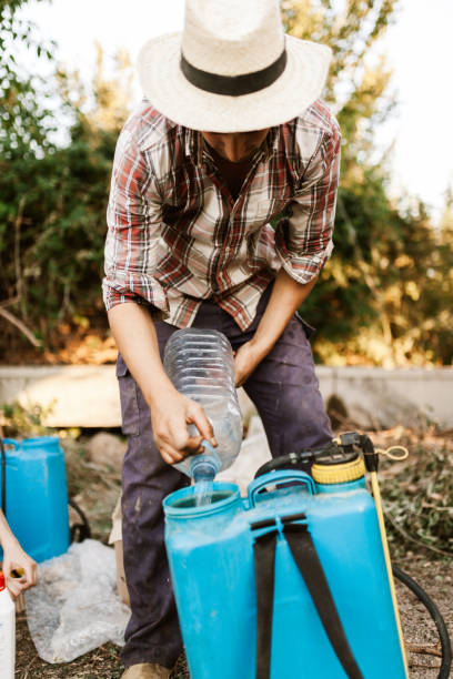 istock Young farmer preparing organic fertilizer with manual pump tank 1211197418