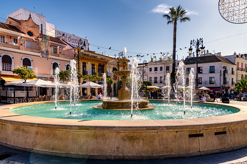 View of water fountain in Cabildo square in old town Sanlucar de Barrameda, Spain, a popular place for tourists full of bars, restaurants and shops.