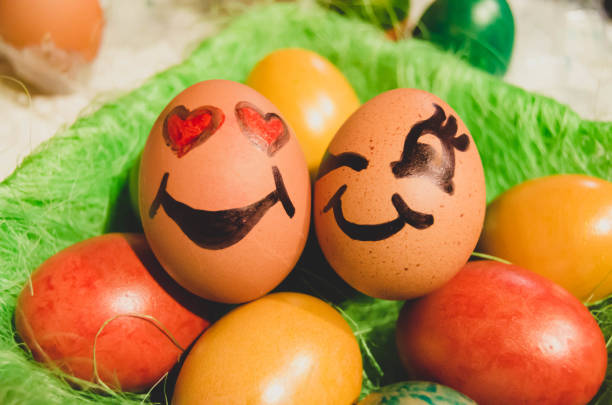 istock Easter decoration. Basket with couple of eggs with face expression surrounded by other colorful eggs 1211199235