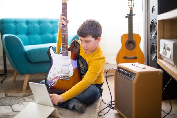 istock Little boy playing electric guitar at home 1211200268