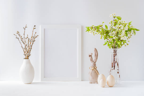 istock Home interior with easter decor. Mockup with a white frame and spring flowers in a vases on a light background 1211201512