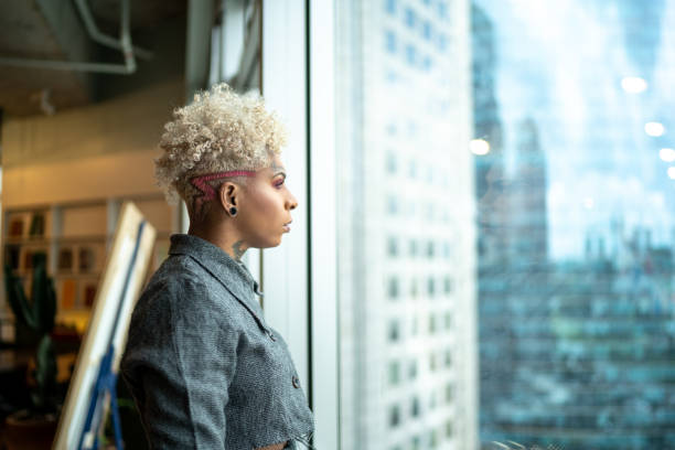 istock Thoughtful tattooed businesswoman looking through window 1211204309