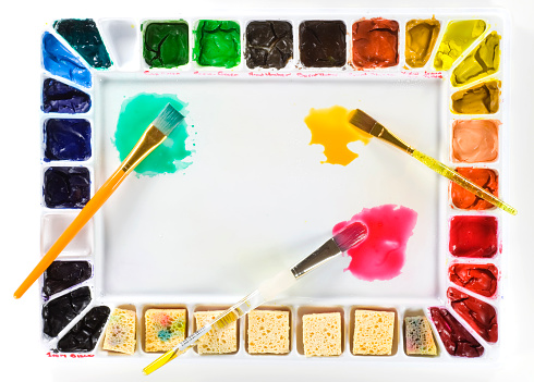 colorful pens arranged in the colors of the rainbow on colorful paper in the course of the rainbow in daylight. the glossy multicolored pencils are made of Wood