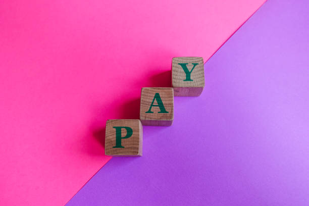 istock PAY, Wood Blocks on Pink and Lilac Background. 1211205375