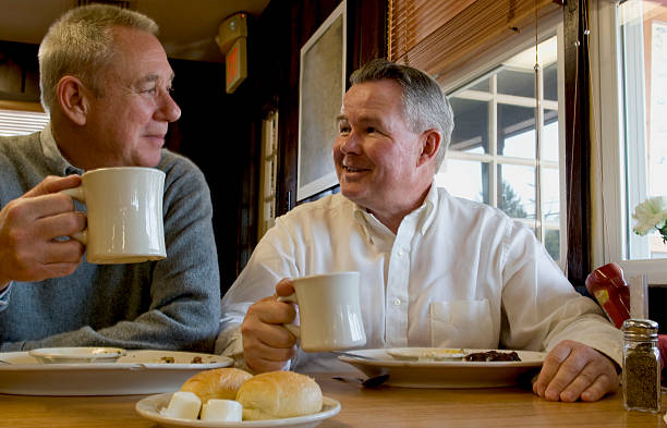 Homens Idosos a comer e beber café - fotografia de stock